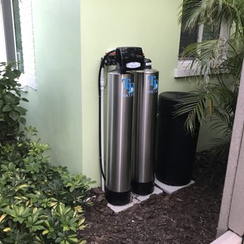 Whole-home water treatment system installed outdoors beside house